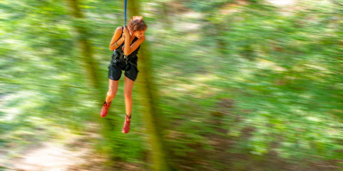 femme qui se balance avec une corde en pendule dans un atelier grimpe d'arbres