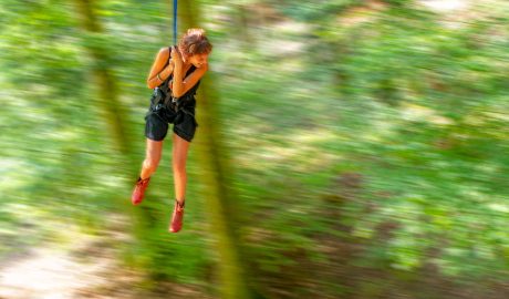 femme qui se balance avec une corde en pendule dans un atelier grimpe d'arbres